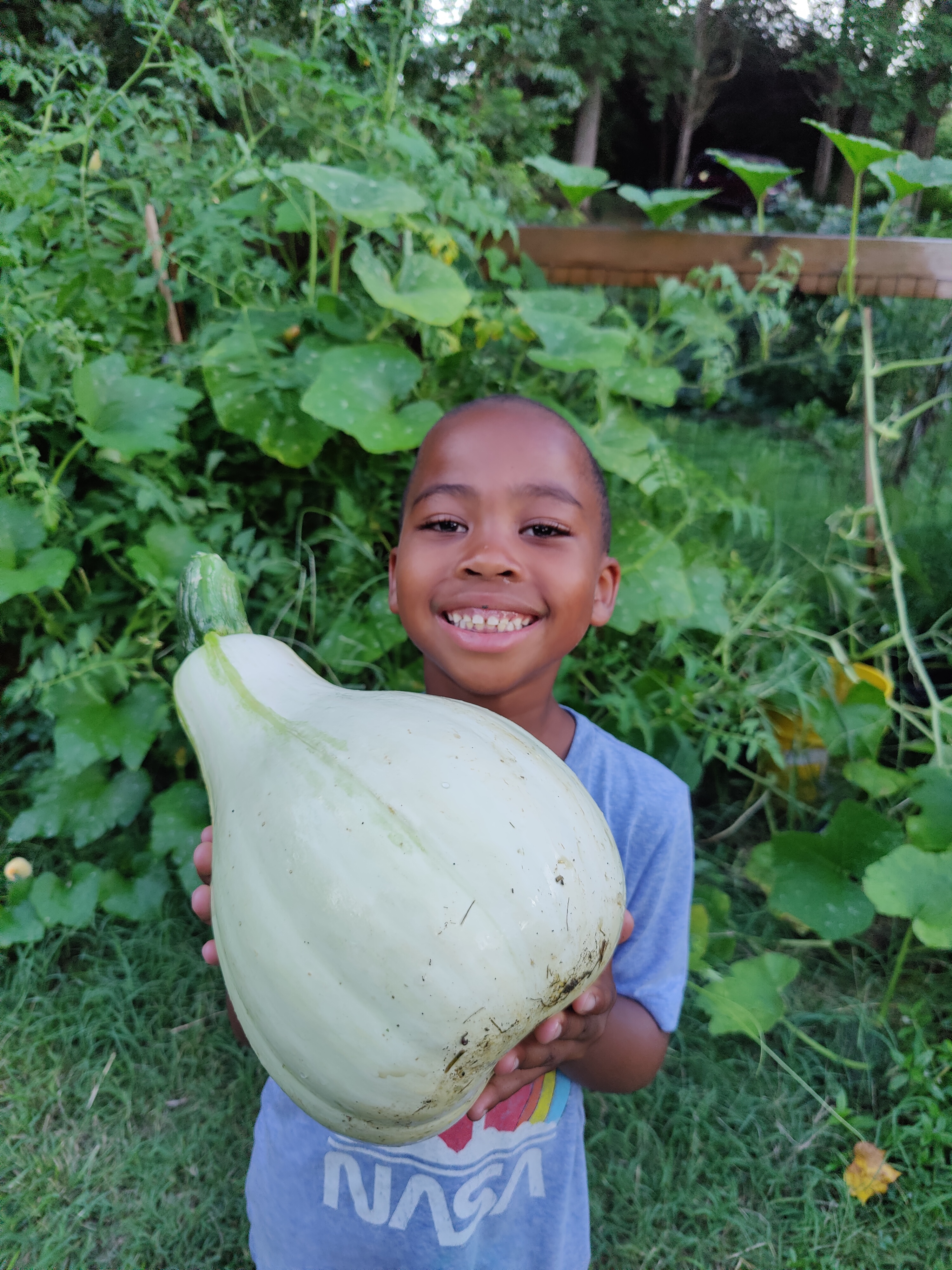Child holds up large gourd with a smile on his face